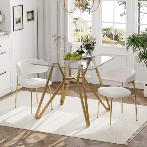 Glass top dining table with gold metal legs and four white chairs