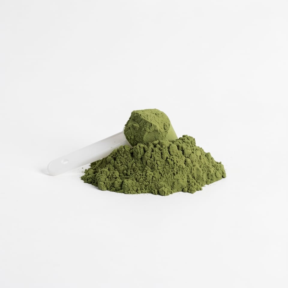 A white plastic container with a green label reading 'GREENS SUPERFOOD POWDER' and a pile of green powder in front of it.